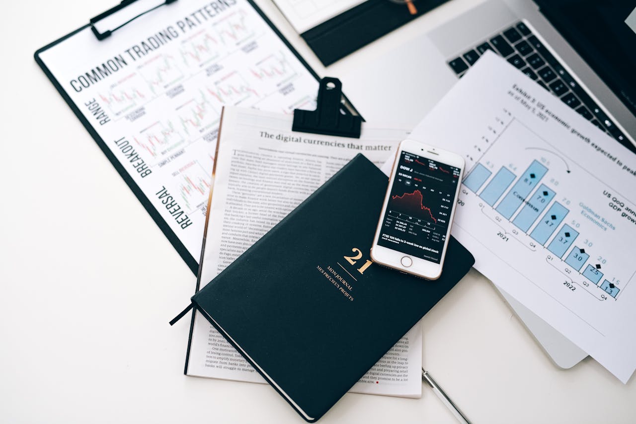 High-angle shot of a stock trading desk with charts, graphs, and a smartphone displaying market trends.