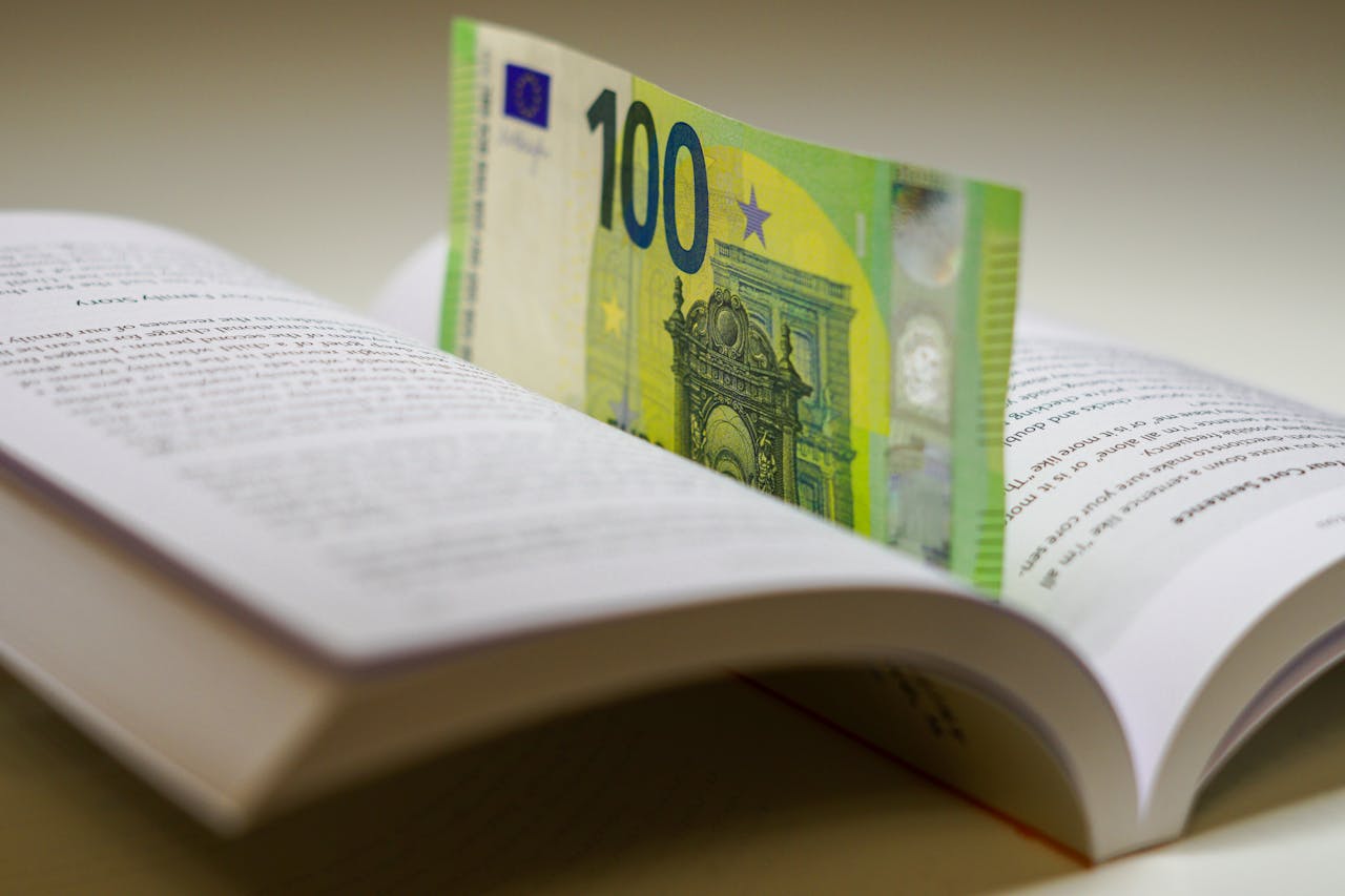 A 100 euro bill used as a bookmark between open pages of a book, symbolizing wealth and knowledge.