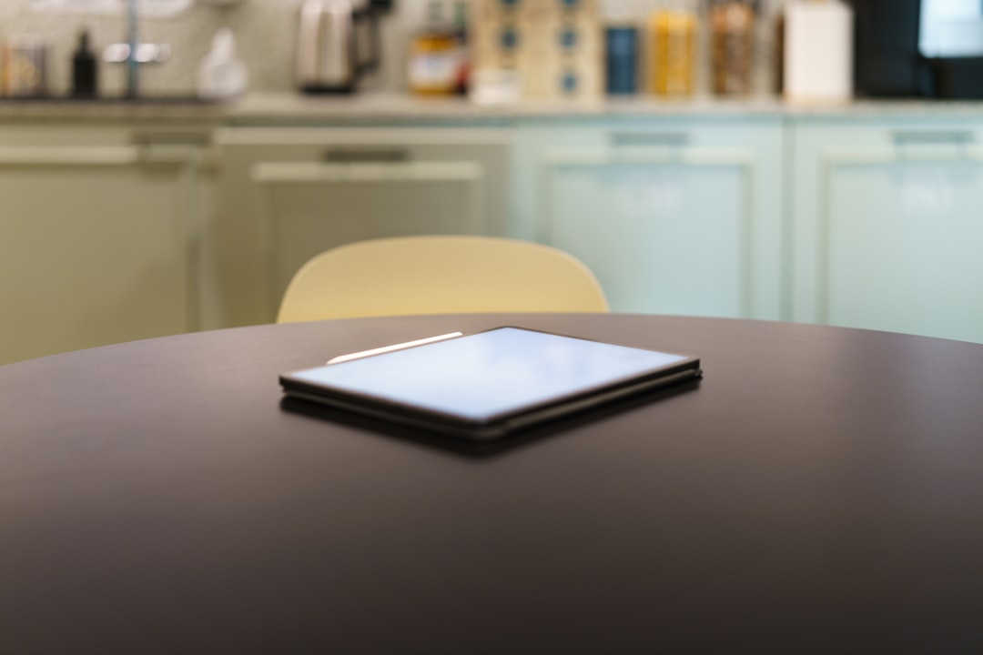 E-reader on kitchen table. Graphic tablet white screen mockup. Home office interior.
